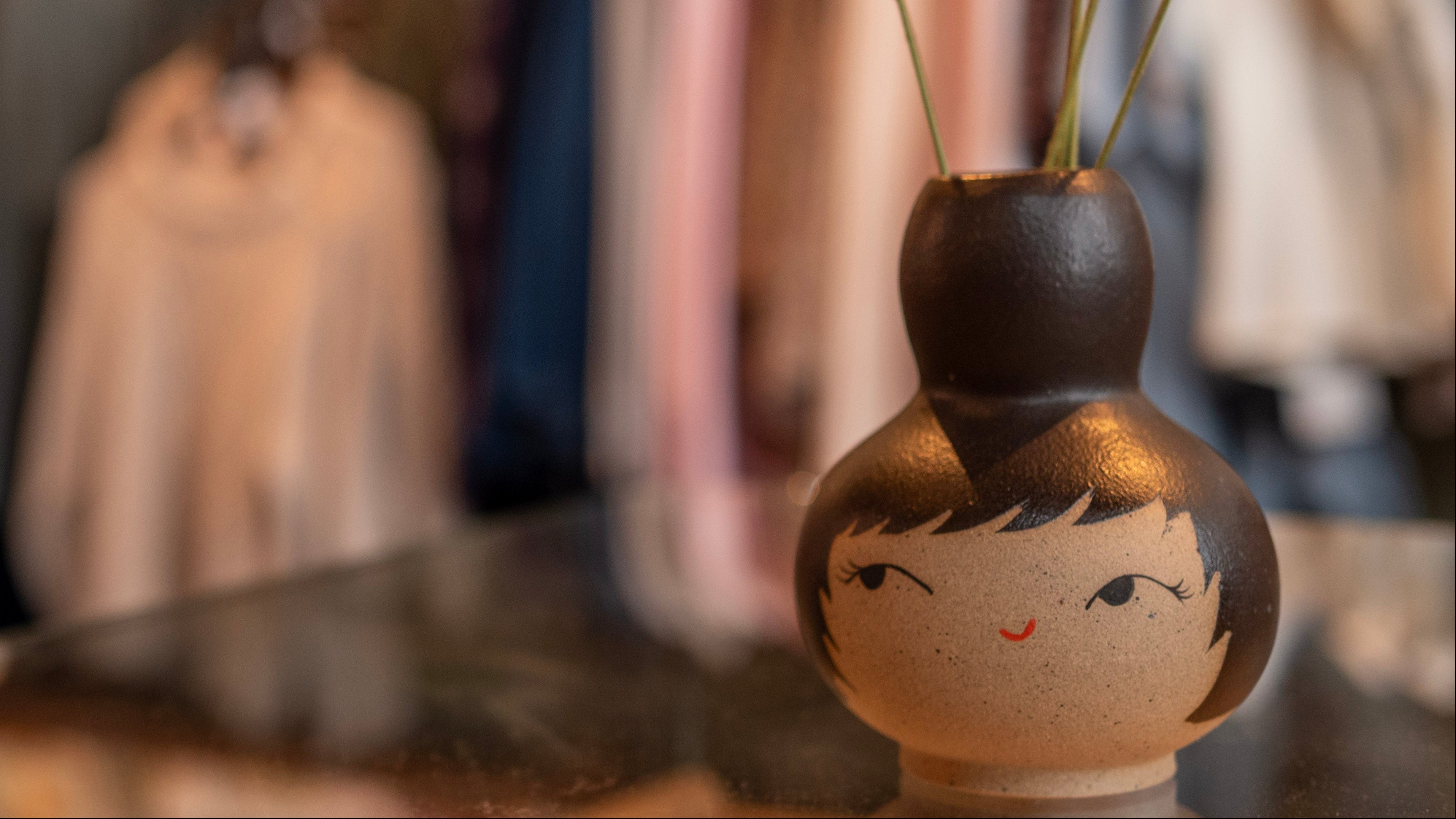 Decorative vase with colorful pom-poms on a clothing rack background